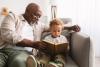 grandfather teaches grandchild with book on the sofa