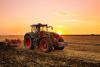 Tractor on the barley field by sunset