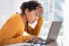 Young woman feeling stressed while looking to laptop